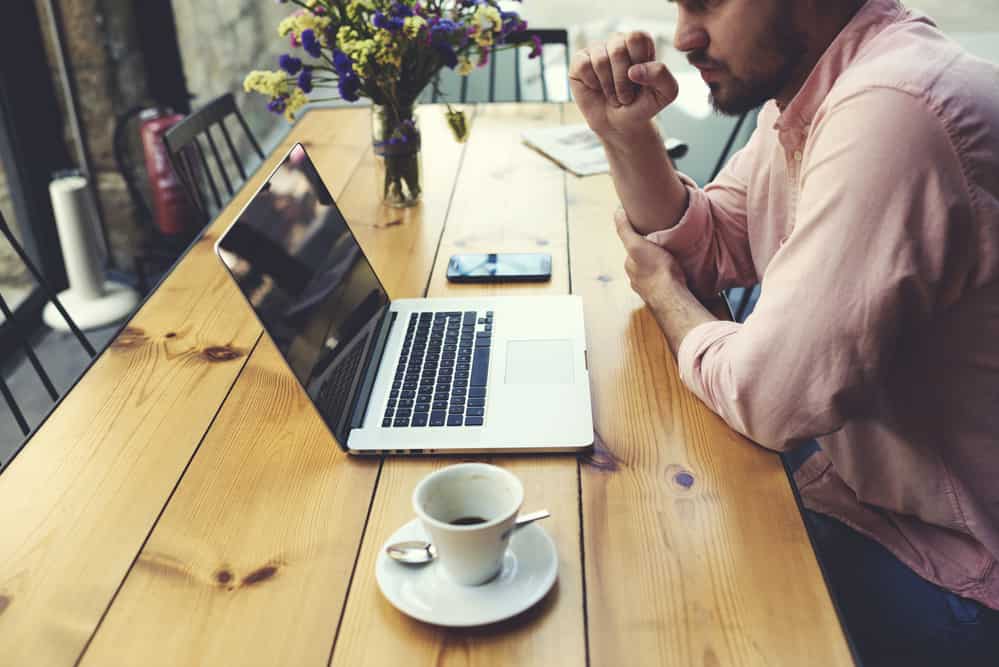 remote working in Europe - Top Tips for Remote Working in Europe Male freelancer connecting to wireless via laptop computer, thoughtful businessman work on notebook while sitting at wooden table in modern coffee shop interior, student reading text or book in cafe
